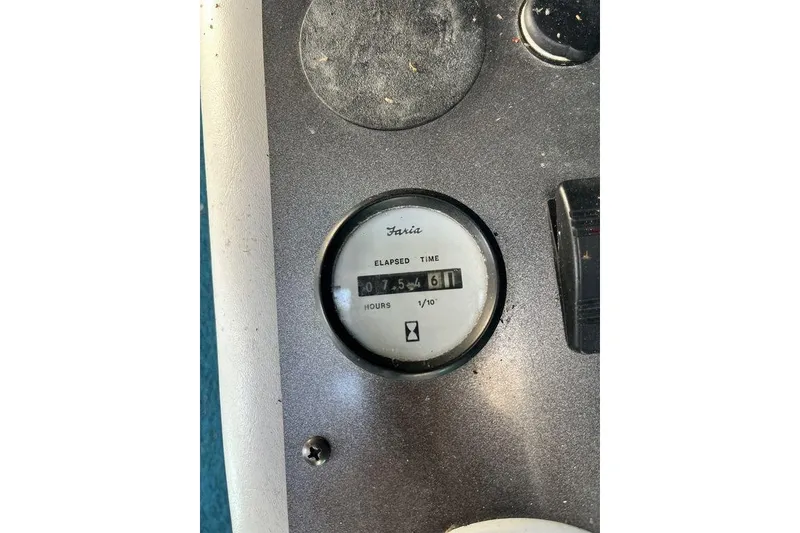 Slide: The Image of 2000 Larson SEI226 boat with teal interior, parked outdoors near a storage facility. - 13