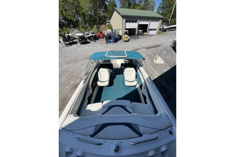 Slide: The Image of 2000 Larson SEI226 boat interior with white and blue seating, parked outdoors. - 14