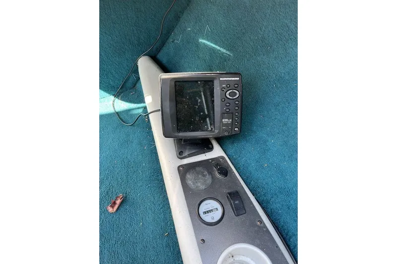 Slide: The Image of 2000 Larson SEI226 boat interior with blue canopy and white seating, parked outdoors. - 16