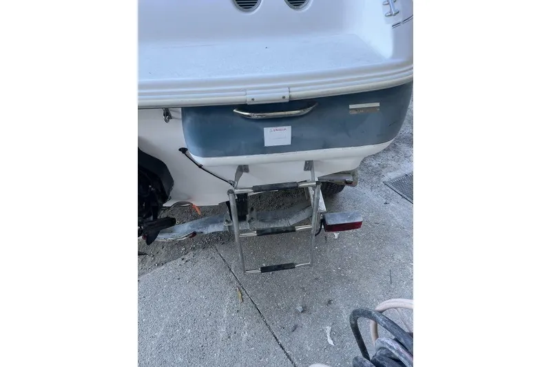 Slide: The Image of 2000 Larson SEI226 boat interior with white seating and teal flooring in storage. - 19