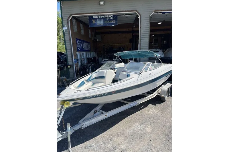 Slide: The Image of 2000 Larson SEI226 boat on trailer outside a garage. - 3