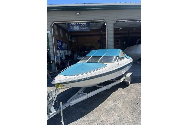 Slide: The Image of 2000 Larson SEI226 boat with white interior, parked in a garage. - 4