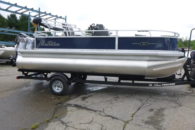 Slide: The Image of 2026 Sun Tracker Bass Buggy 18 DLX pontoon boat on trailer, parked outdoors. - 3