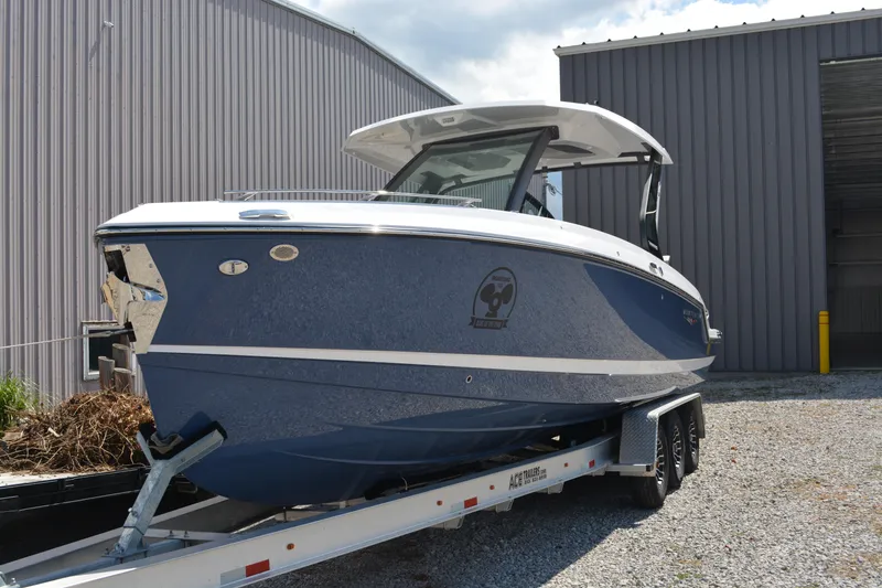 The Image of 2026 Monterey Elite 30 OB boat on trailer, parked near a metal building. - 0