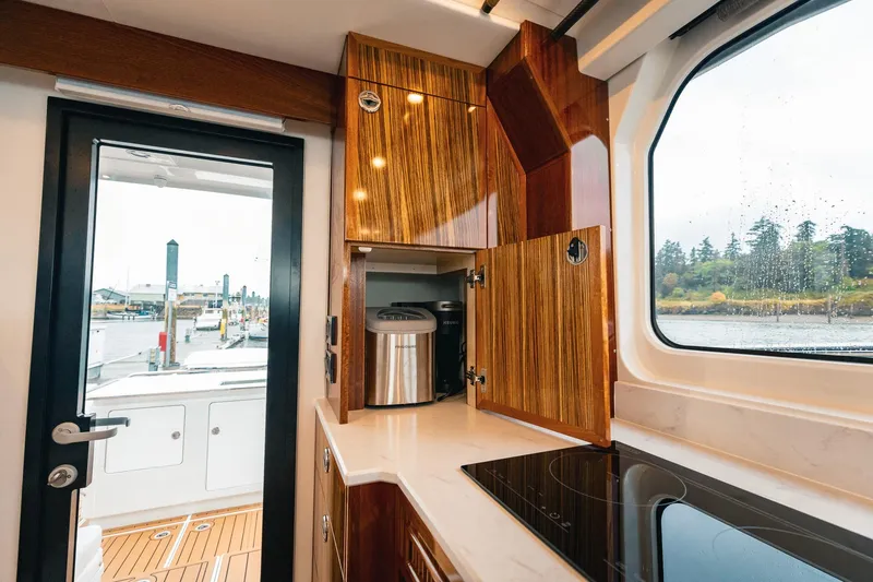 Slide: The Image of Modern kitchen interior of 2025 Lindell 48' yacht with sleek wood cabinetry and scenic window view. - 14