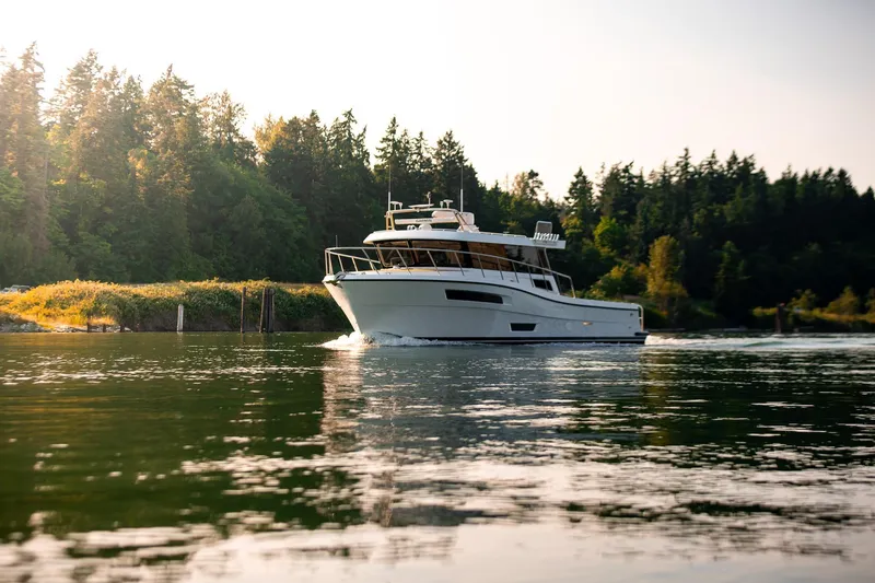Slide: The Image of 2025 Lindell 48' yacht cruising on a serene forest-lined waterway. - 2