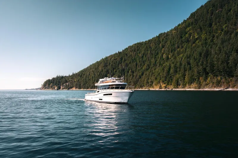 Slide: The Image of 2025 Lindell 48' yacht cruising near a forested coastline under a clear blue sky. - 49