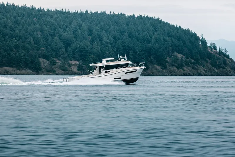 Slide: The Image of 2025 Lindell 48' yacht cruising on a serene lake with forested hills in the background. - 55