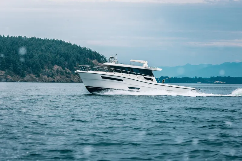 Slide: The Image of 2025 Lindell 48' yacht cruising on open water near forested coastline. - 56