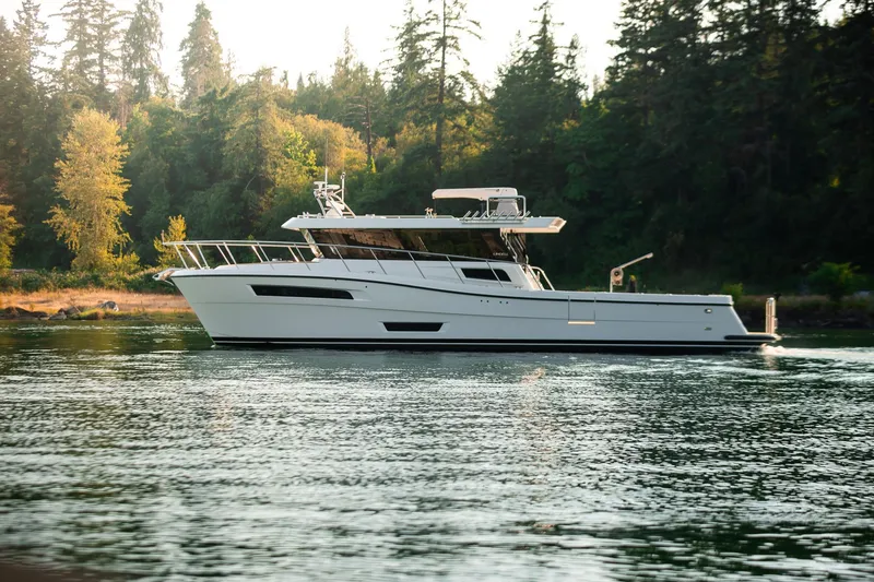 Slide: The Image of 2025 Lindell 48' yacht cruising on a serene lake with forested background. - 57