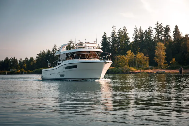 Slide: The Image of 2025 Lindell 48' yacht cruising on a serene lake with forested shoreline. - 58