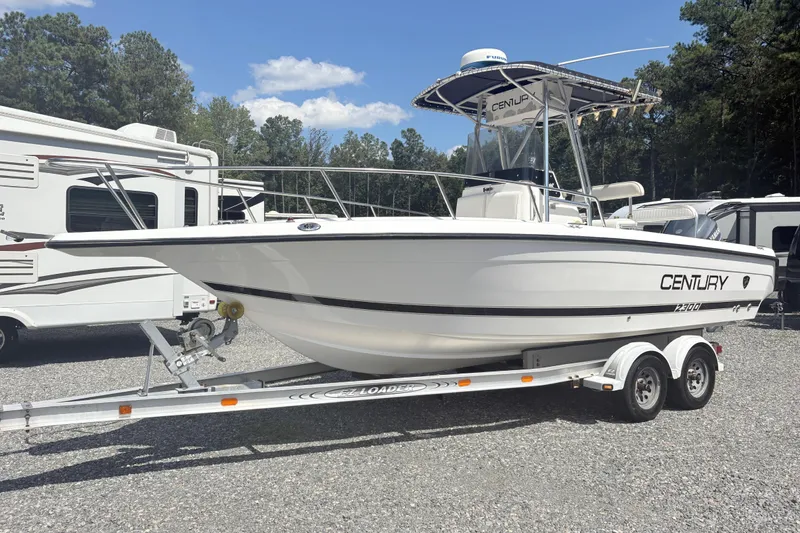 The Image of 2002 Century 2300 Center Console boat on trailer, parked outdoors near RVs. - 1