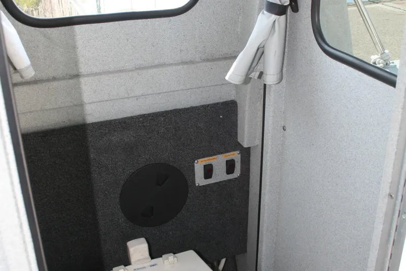 Slide: The Image of Interior of 2007 Harbercraft 2425 Pilot House boat, featuring control switches and storage. - 14