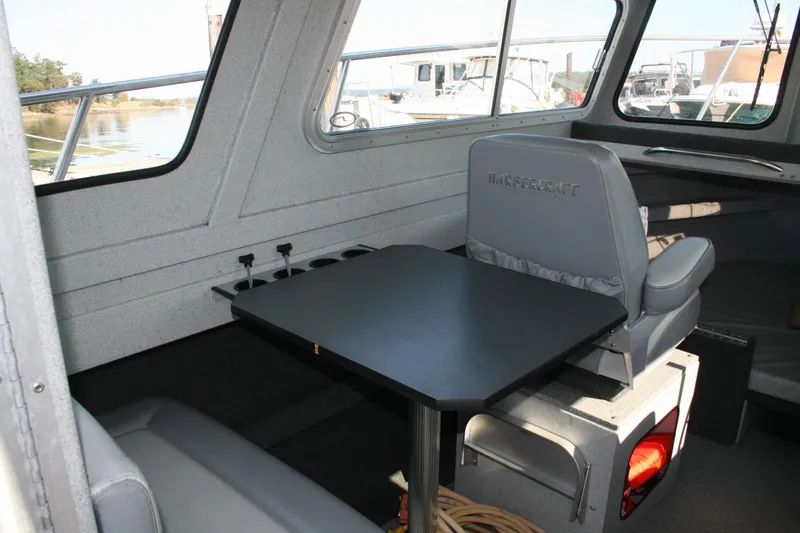 Slide: The Image of 2007 Harbercraft 2425 Pilot House interior with seating and table, docked by the water. - 8