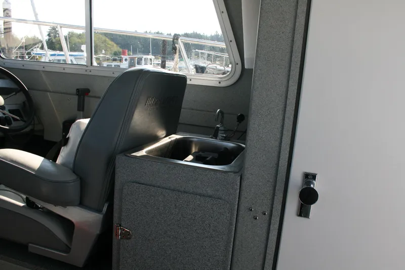 Slide: The Image of 2007 Harbercraft 2425 Pilot House interior with steering wheel and compact sink. - 9