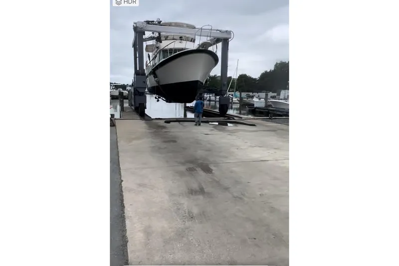 Slide: The Image of 1980 Hatteras 42 LRC yacht being lifted at a marina dock. - 34
