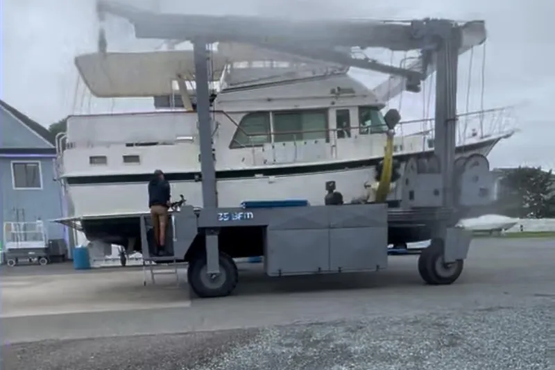 Slide: The Image of 1980 Hatteras 42 LRC yacht being transported by a large lift at a marina. - 35