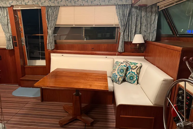 Slide: The Image of Interior of 1980 Hatteras 42 LRC yacht with wooden table, white seating, and floral cushions. - 38