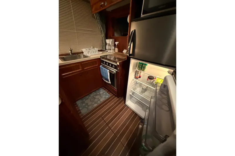 Slide: The Image of 1980 Hatteras 42 LRC yacht kitchen with open fridge, stove, and sink. - 42