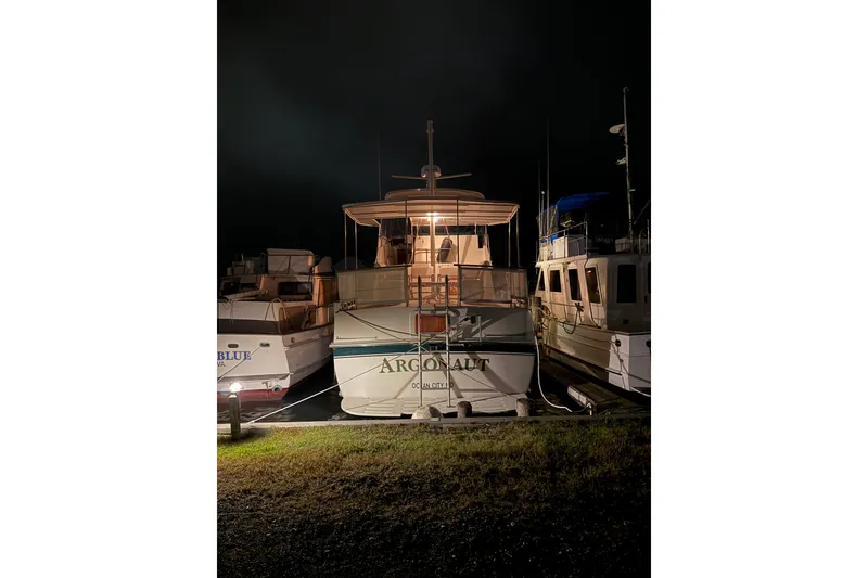 Slide: The Image of 1980 Hatteras 42 LRC yacht docked at night, illuminated, with neighboring boats. - 45