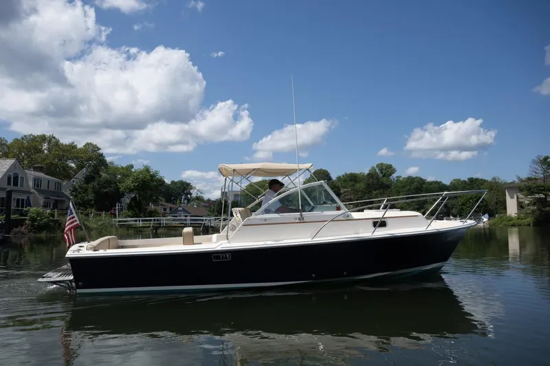 The Image of 2004 Hunt Yachts Surfhunter 25 cruising on a calm lake under a clear blue sky. - 0