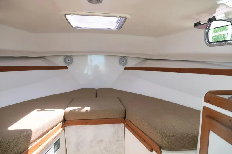 Slide: The Image of 2004 Hunt Yachts Surfhunter 25 cabin interior with cushioned seating and wooden accents. - 29