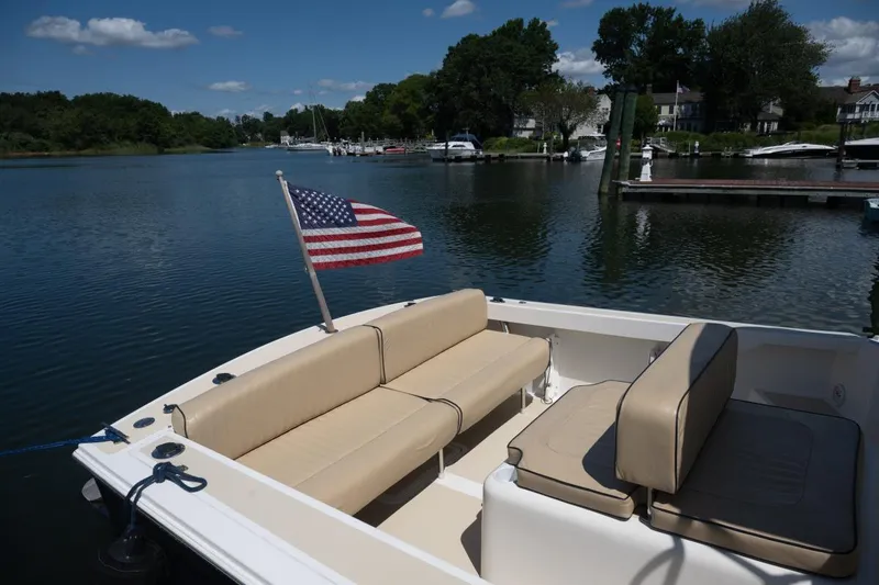 Slide: The Image of 2004 Hunt Yachts Surfhunter 25 with American flag, docked on a serene lake. - 8