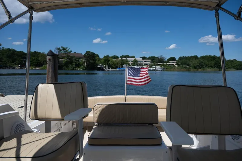 Slide: The Image of 2004 Hunt Yachts Surfhunter 25 interior with American flag, docked by a scenic lake. - 9
