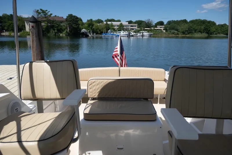 Slide: The Image of 2004 Hunt Yachts Surfhunter 25 interior with seating, docked by a serene lake. - 10