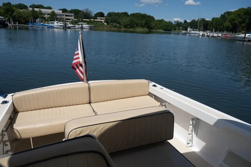Slide: The Image of 2004 Hunt Yachts Surfhunter 25 with beige seating, American flag, on a serene lake. - 11