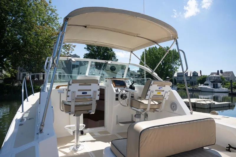 Slide: The Image of 2004 Hunt Yachts Surfhunter 25 with canopy, docked in a scenic marina setting. - 13