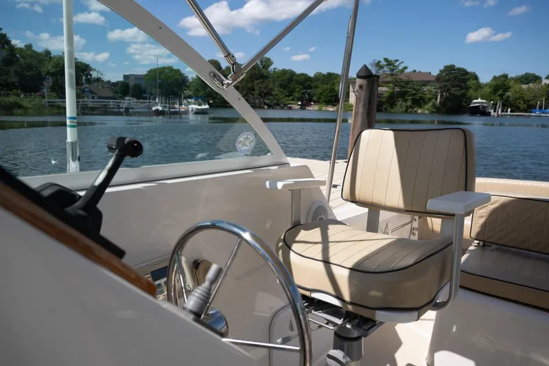 Slide: The Image of 2004 Hunt Yachts Surfhunter 25 helm with beige seating, docked by a scenic lake. - 18