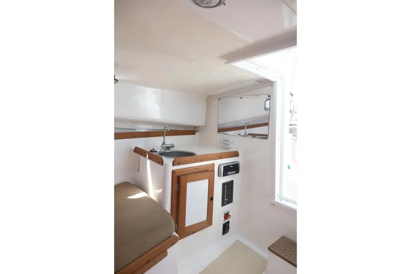 Slide: The Image of 2004 Hunt Yachts Surfhunter 25 cabin interior with sink, wooden accents, and control panel. - 28