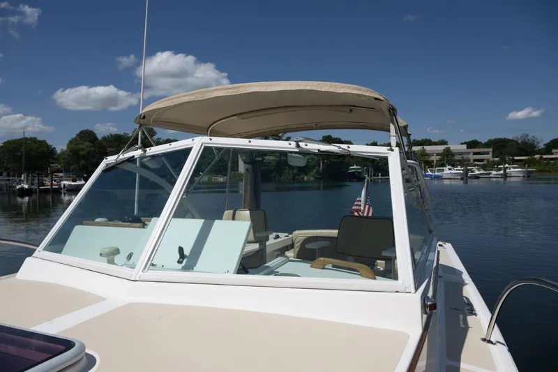 Slide: The Image of 2004 Hunt Yachts Surfhunter 25 on calm water, featuring a beige canopy and American flag. - 33