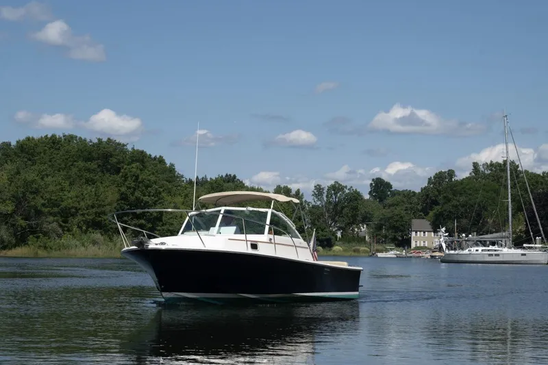 Slide: The Image of 2004 Hunt Yachts Surfhunter 25 on calm water, surrounded by trees and boats. - 35