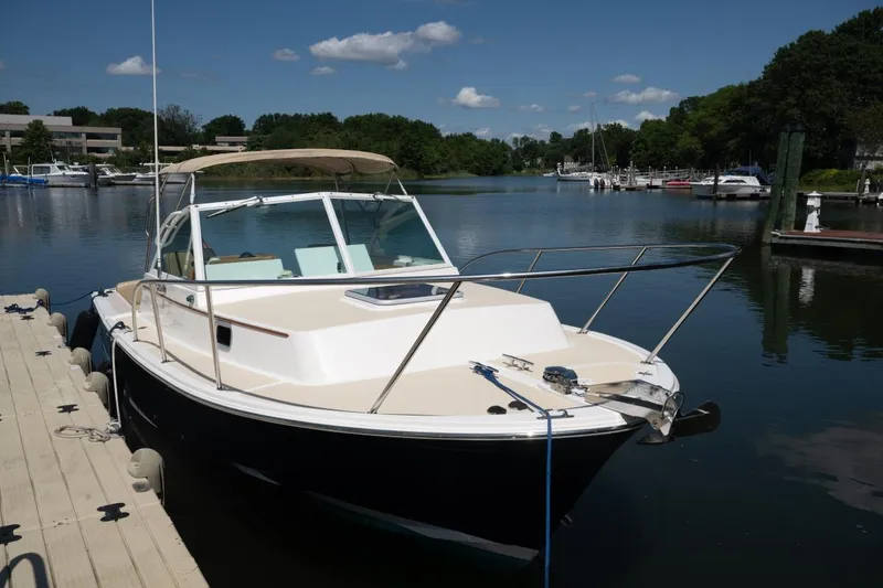 Slide: The Image of 2004 Hunt Yachts Surfhunter 25 docked on a serene lake under a clear blue sky. - 37