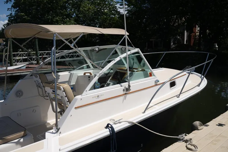 Slide: The Image of 2004 Hunt Yachts Surfhunter 25 docked, featuring a sleek design and beige canopy. - 5