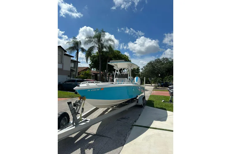 Slide: The Image of 2019 Concept 27' CC boat on trailer under clear blue sky with palm trees. - 1