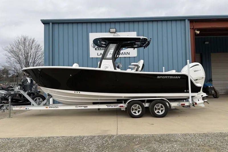 The Image of 2026 Sportsman Heritage 231 Center Console boat on trailer outside blue building. - 0