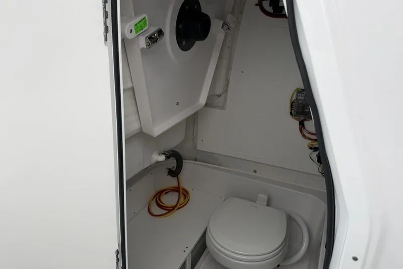Slide: The Image of Interior of 2026 Sportsman Heritage 231 Center Console boat, featuring a compact marine toilet. - 16