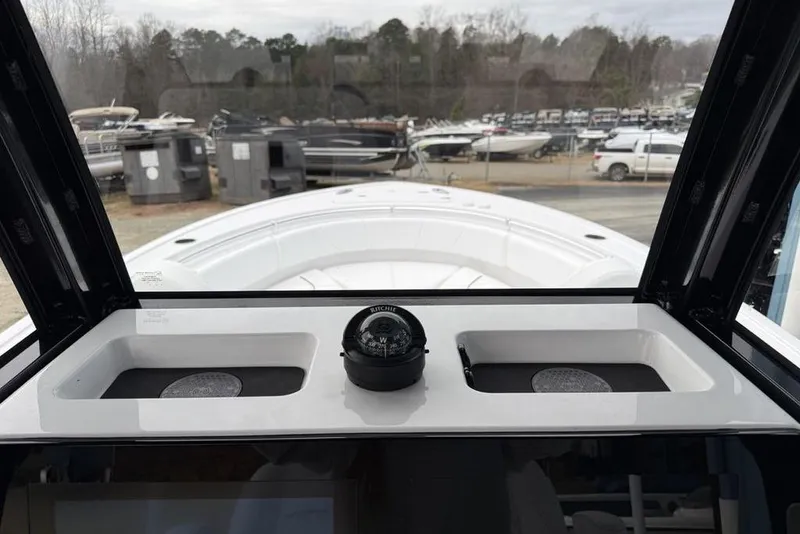 Slide: The Image of 2026 Sportsman Heritage 231 Center Console boat interior with compass, docked among other boats. - 23