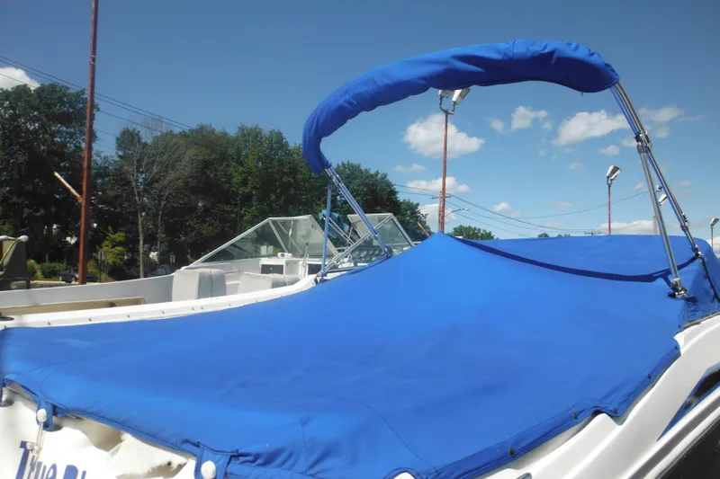 Slide: The Image of 2011 Sea Ray 205 Sport boat with blue cover and canopy under clear sky. - 15