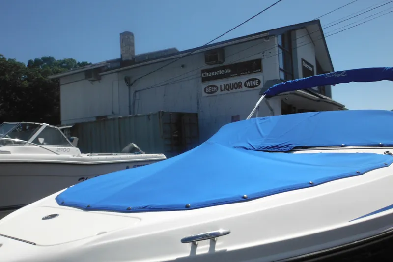 Slide: The Image of 2011 Sea Ray 205 Sport boat with blue cover, parked near a liquor store. - 9