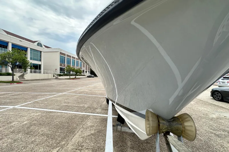 Slide: The Image of 1999 Contender 23 Open boat on trailer in parking lot near modern building. - 21