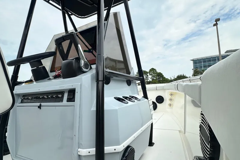Slide: The Image of 1999 Contender 23 Open boat console with steering wheel and controls, under a cloudy sky. - 32