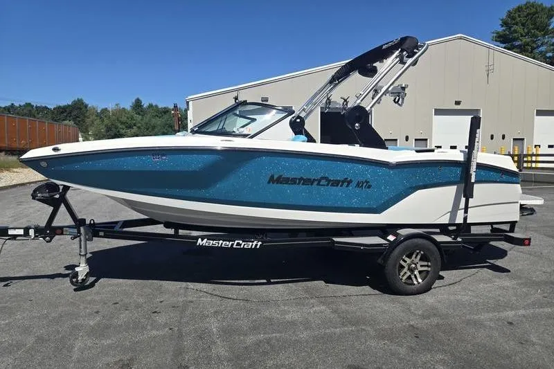 Slide: The Image of 2020 MasterCraft NXT20 boat on trailer, parked outdoors near industrial building. - 14