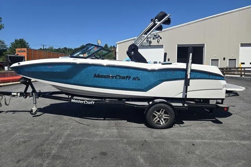 Slide: The Image of 2020 MasterCraft NXT20 boat on trailer, parked outdoors near industrial building. - 20