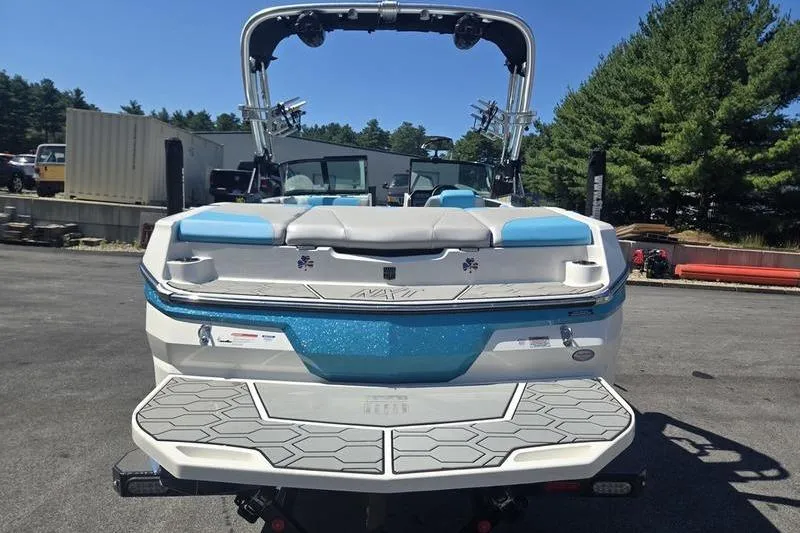 Slide: The Image of 2020 MasterCraft NXT20 boat, rear view, parked outdoors with trees in the background. - 23