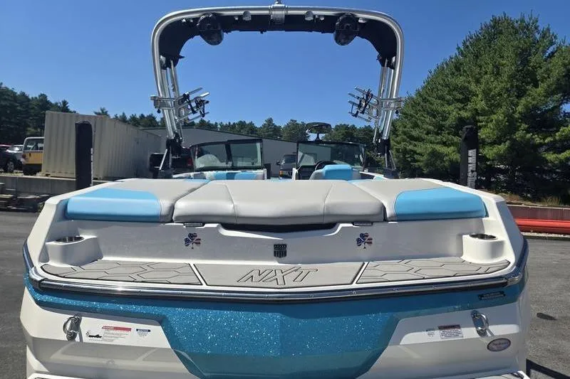 Slide: The Image of 2020 MasterCraft NXT20 boat with blue and white seating, parked outdoors. - 3