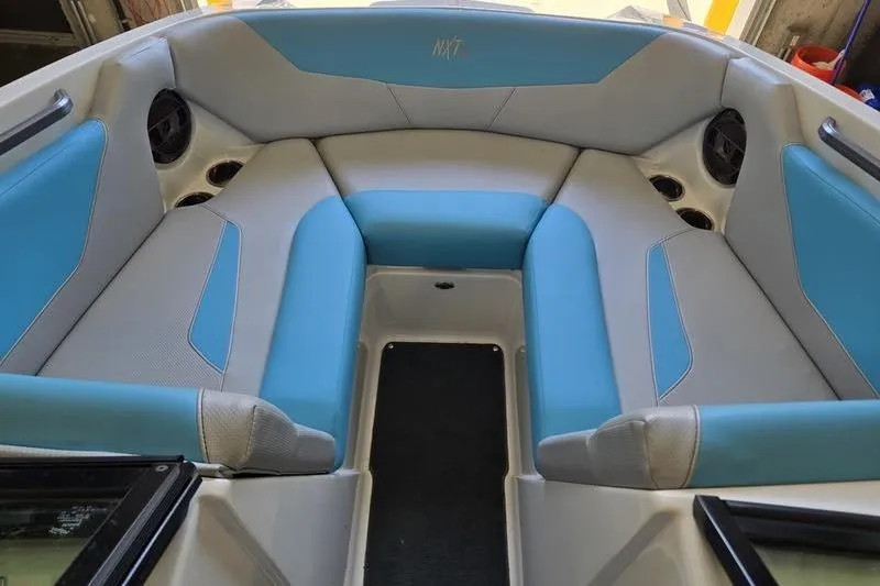 Slide: The Image of 2020 MasterCraft NXT20 boat interior with blue and gray seating, cup holders, and speakers. - 9